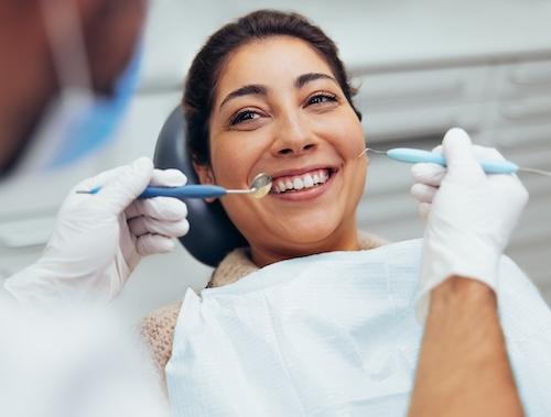 Woman smiling in dental chair getting teeth cleaned, indianapolis in