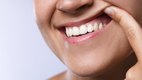 Woman pulling back lip to reveal red, inflamed gums